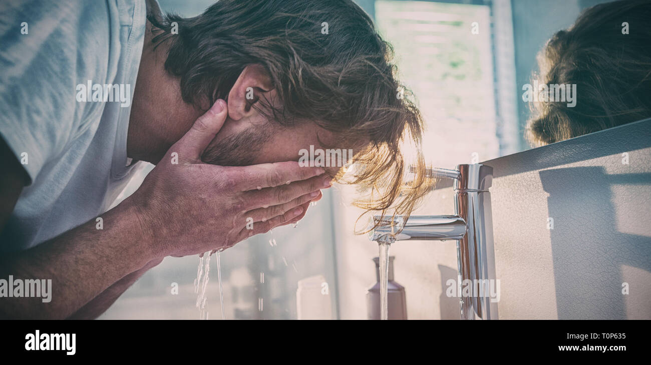 Man washing his face with water in bathroom Stock Photo