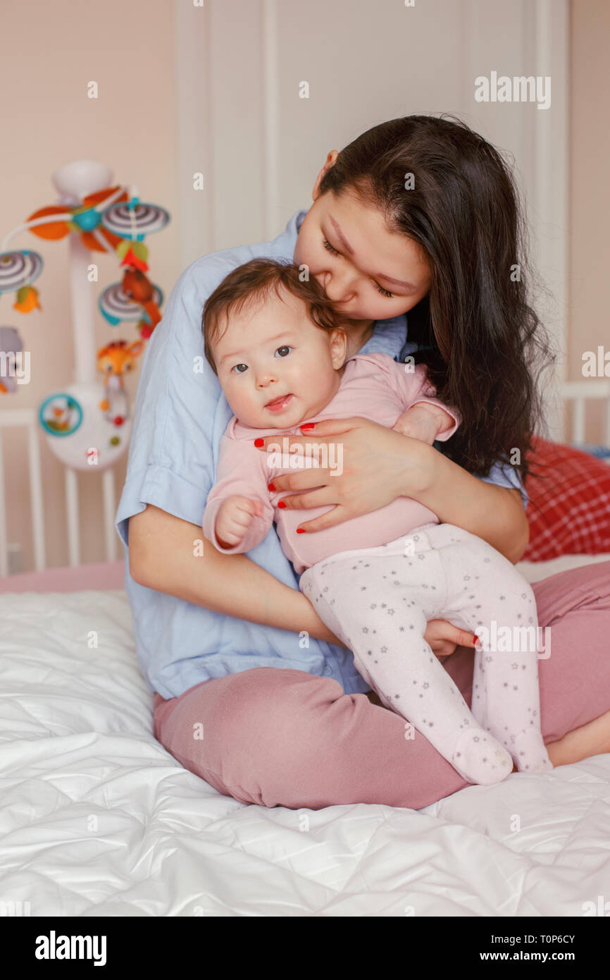 Portrait of beautiful mixed race Asian mother kissing touching embracing her cute adorable newborn infant baby. Early development and health care life Stock Photo