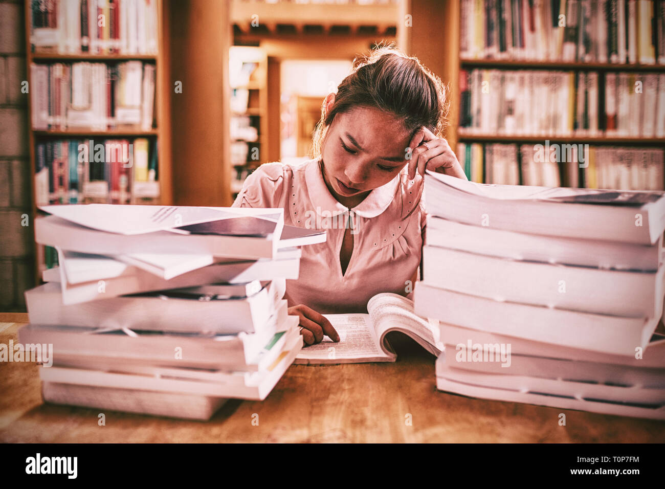 Tensed young woman studying in library Stock Photo