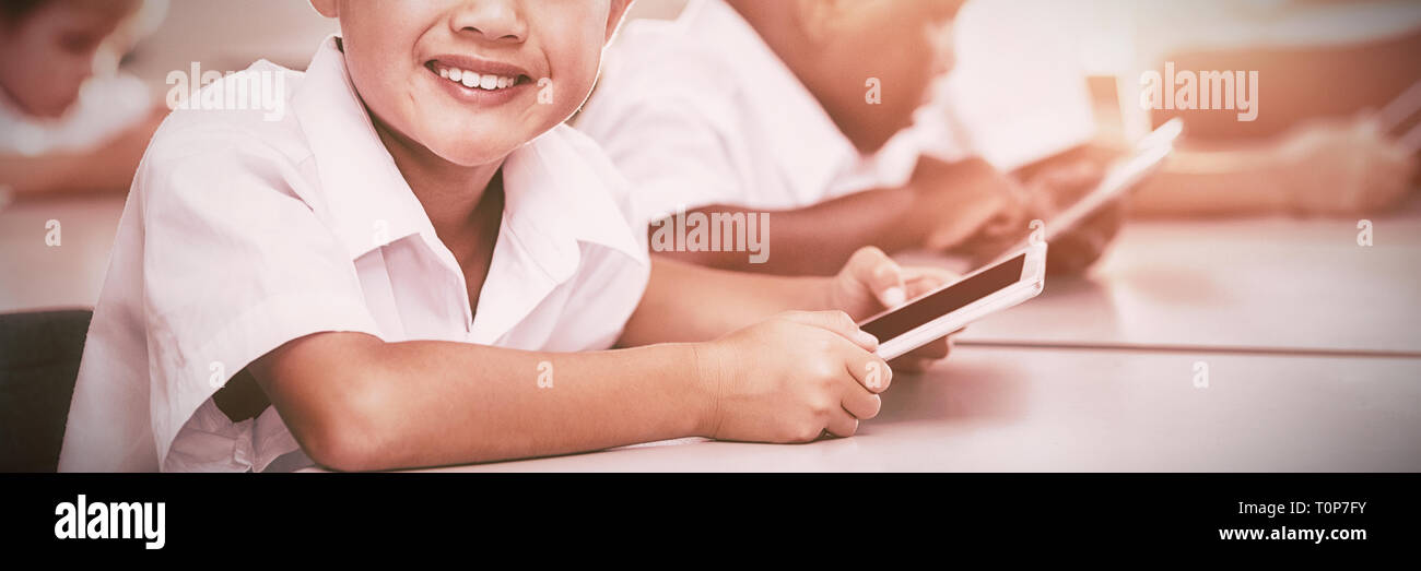 School kids using mobile phone in classroom Stock Photo