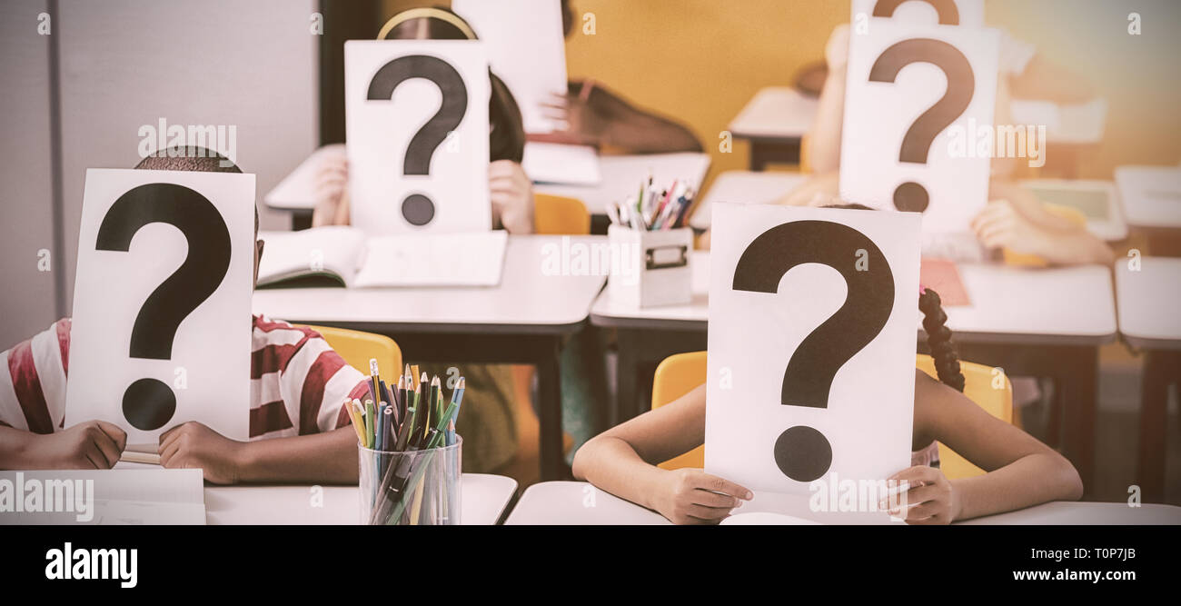 School kids covering their face with question mark sign Stock Photo