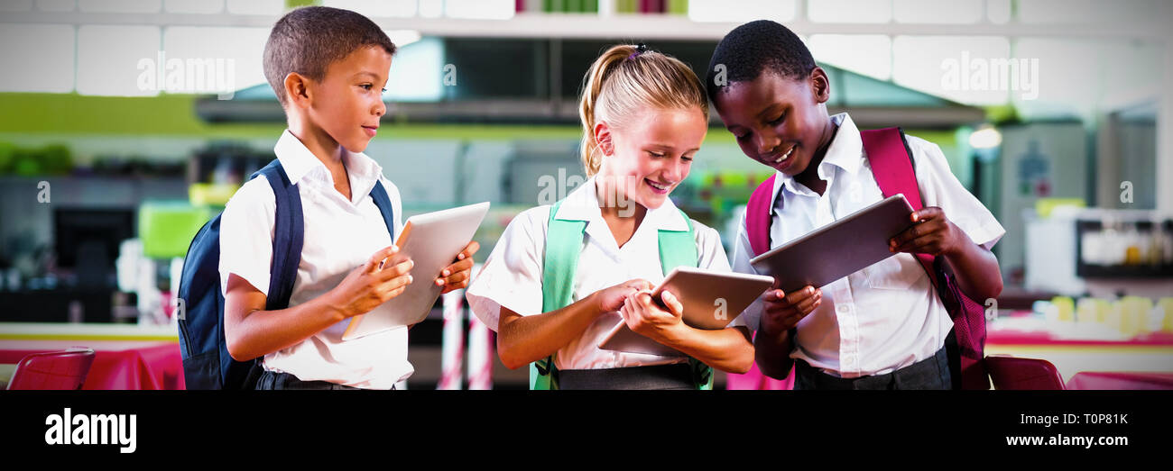 School kids using digital tablet in school cafeteria Stock Photo
