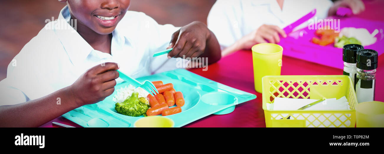 Boy and girl in school uniforms having lunch in school cafeteria Stock Photo