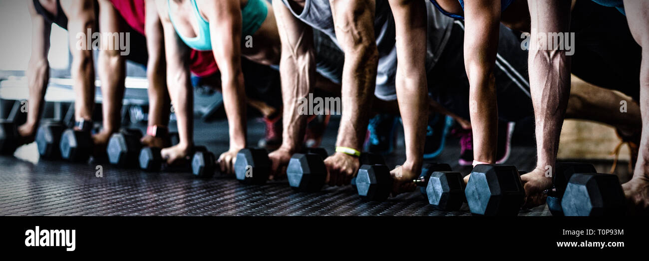 People doing push ups with dumbbell in gym Stock Photo