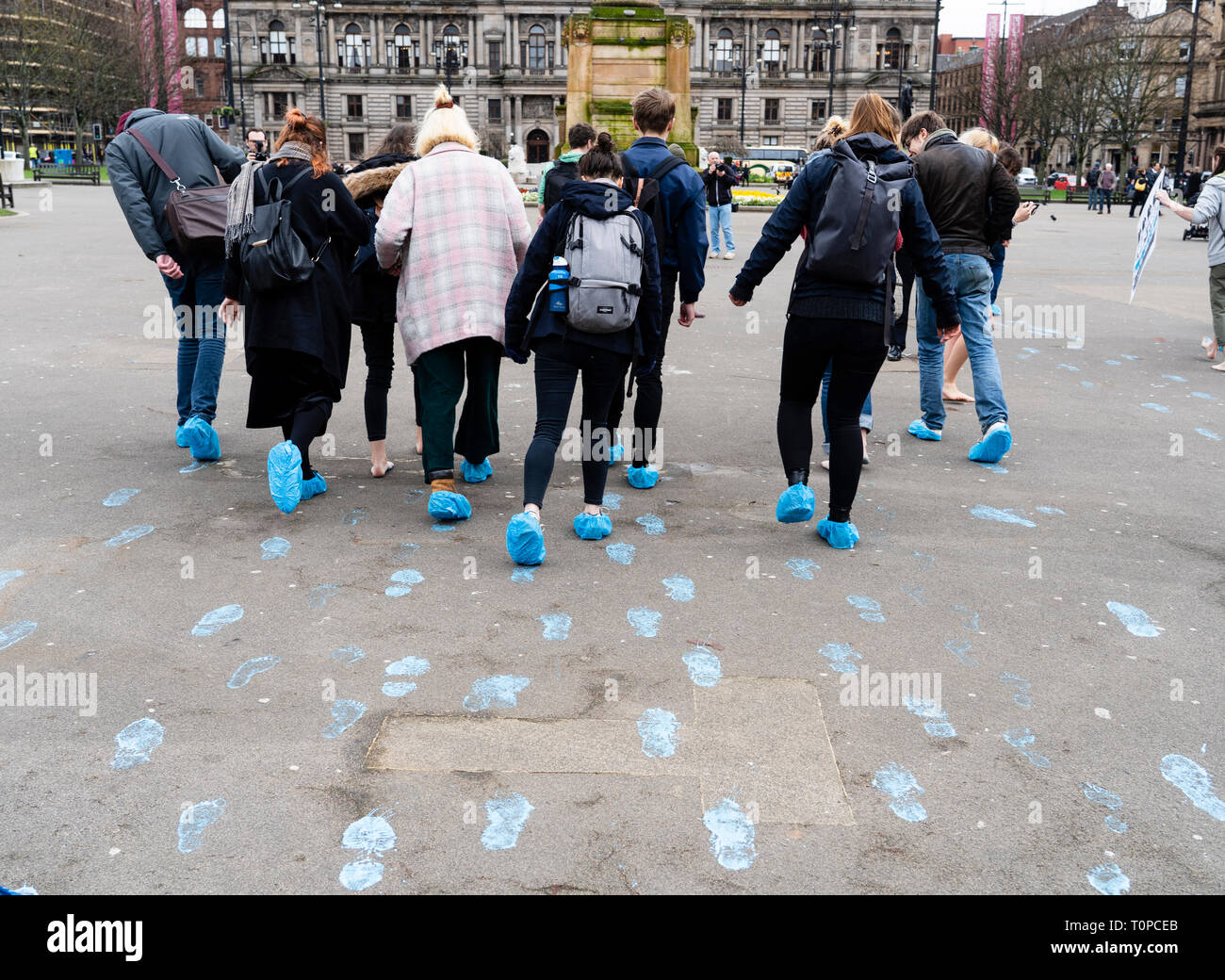 Glasgow, Scotland, UK. 21 March, 2019. A  'Blue Wave' demonstration by the Extinction Rebellion climate change protest group saw protesters make blue footprints, made from water-soluble paint, across George Square to the City Chambers. The peaceful protest briefly held up traffic. The Group aims to highlight threat of rising water levels in the River Clyde and of global climate change. Credit: Iain Masterton/Alamy Live News Stock Photo