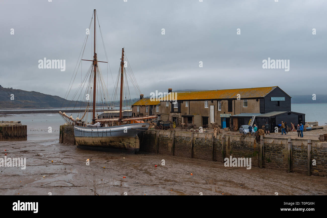 Lyme Regis, Dorset, UK. 21st March 2019. Traditional 1907 sailing Ship 'Irene' moored in Lyme Regis harbour as the 100 foot ketch and the historic Cobb buildings are transformed into a movie set in readiness for continued filming of Ammonite starring Kate Winslet and Saoirse Ronan. Directed by Francis Lee, the fictional drama portrays famous fossil hunter Mary Anning as a gay woman sparking debate among historians and on social media.  The film is expected to bring a welcome boost for tourism and the local economy. Credit: Celia McMahon/Alamy Live News Stock Photo