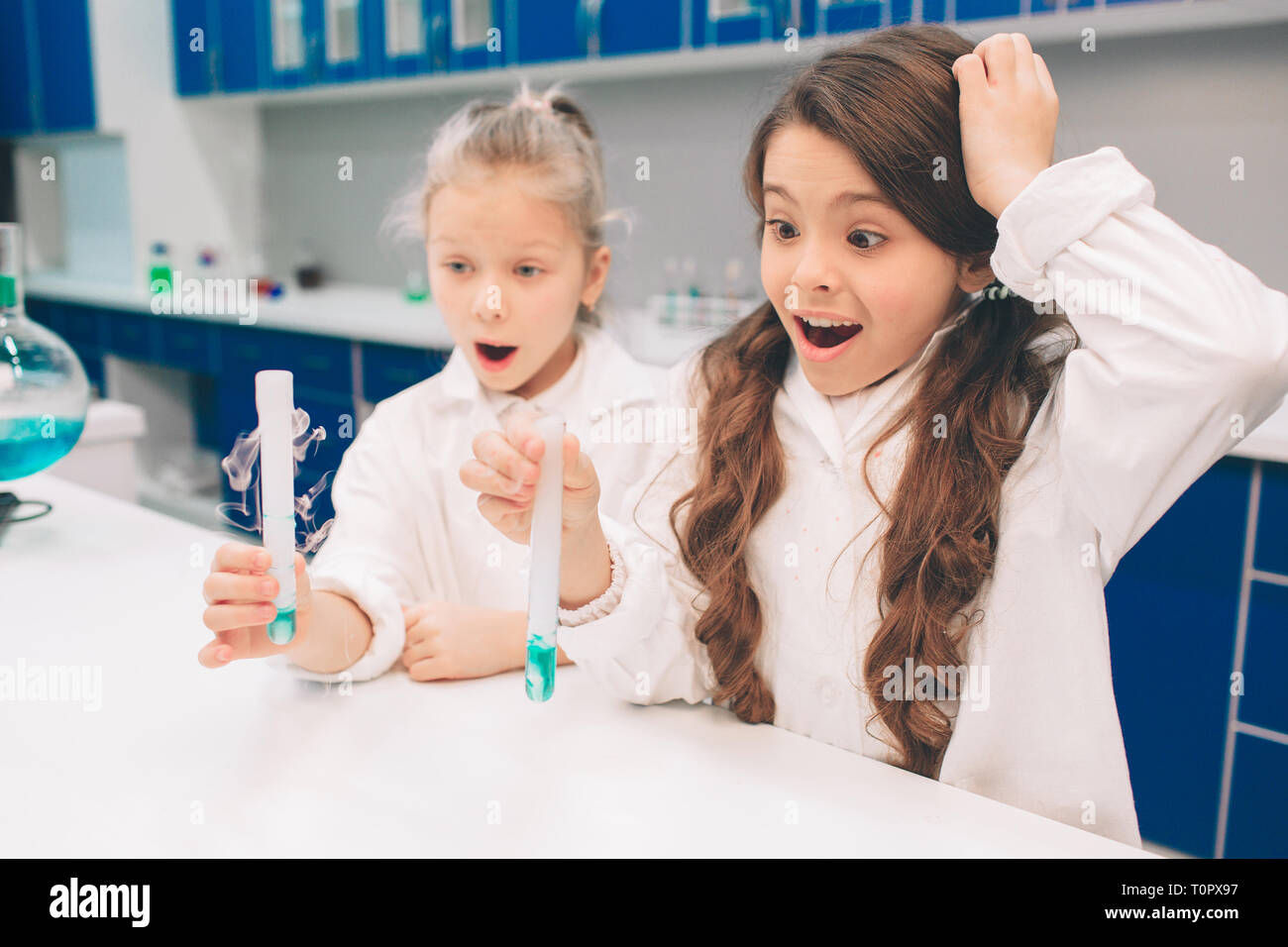 Two little kids in lab coat learning chemistry in school laboratory. Studying ingredients for experiments . Young scientists in protective glasses mak Stock Photo