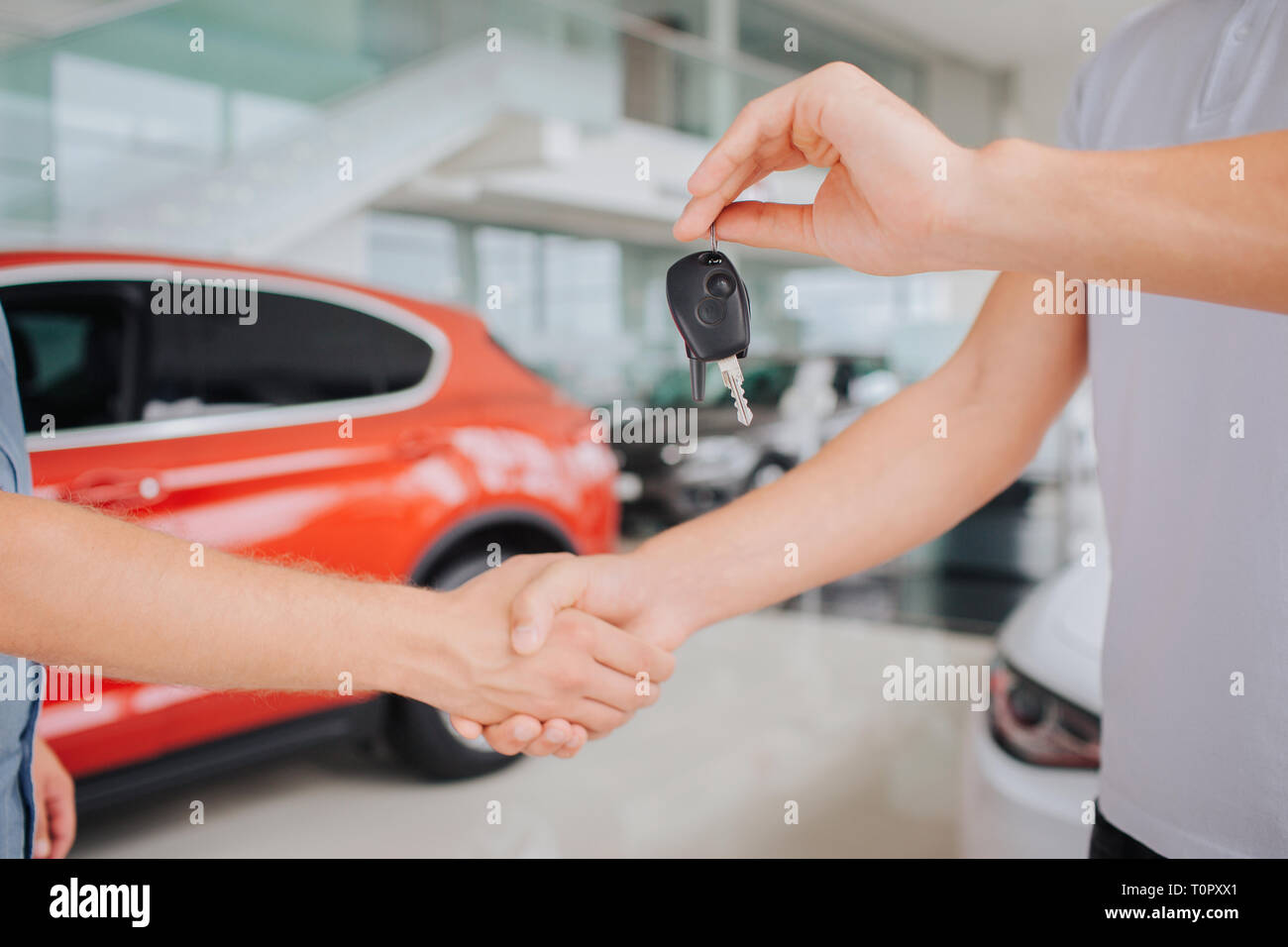 Picture of men shaking eah other's hands. Guy on right hold key in left ...