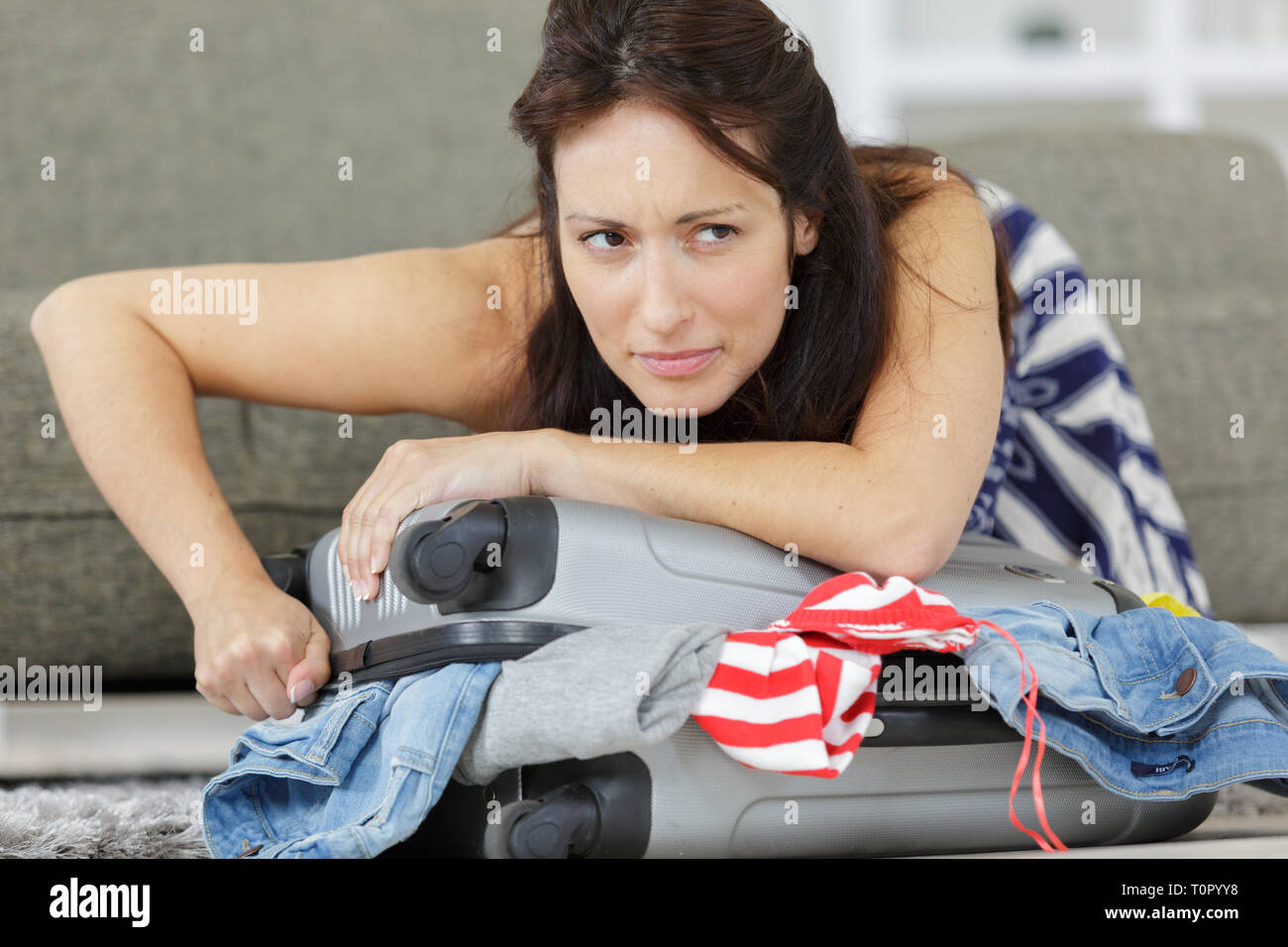 woman struggling to close suitcase Stock Photo