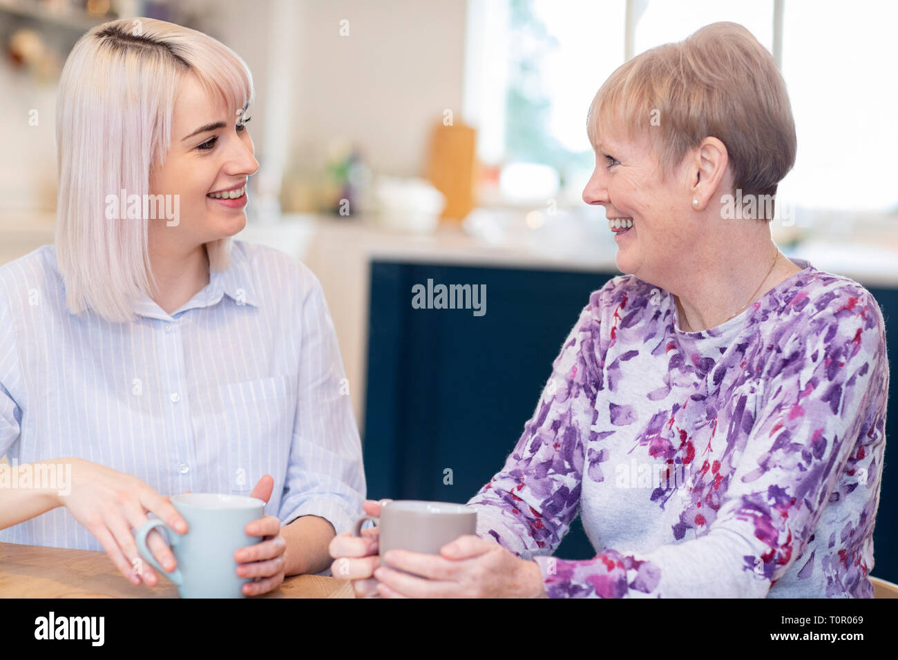 Young Woman Taking Time To Visit Senior Female Neighbor And Talk Stock Photo