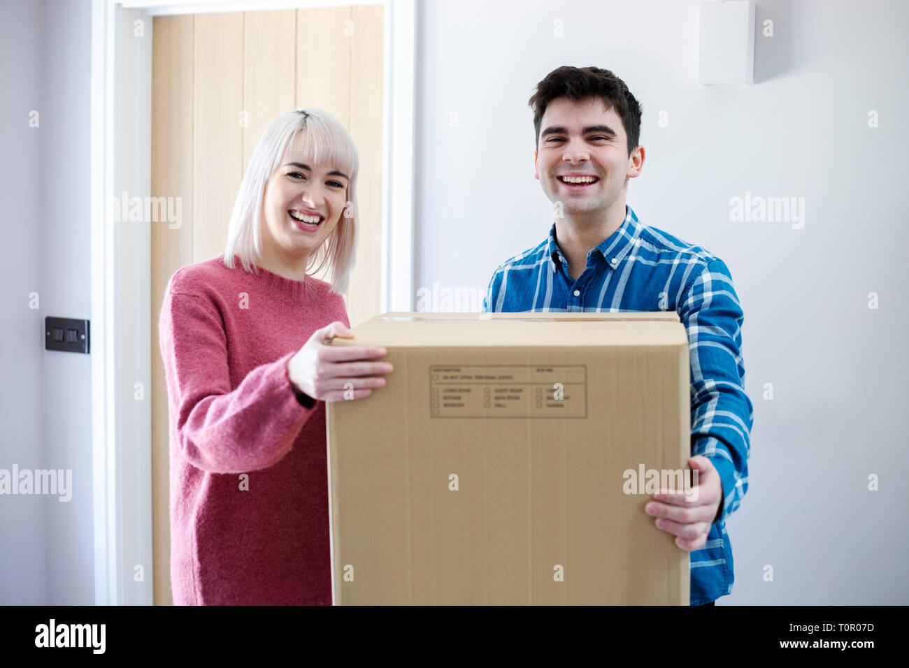 Portrait Of Young Couple Carrying Boxes Into New Home On Moving Day Stock Photo