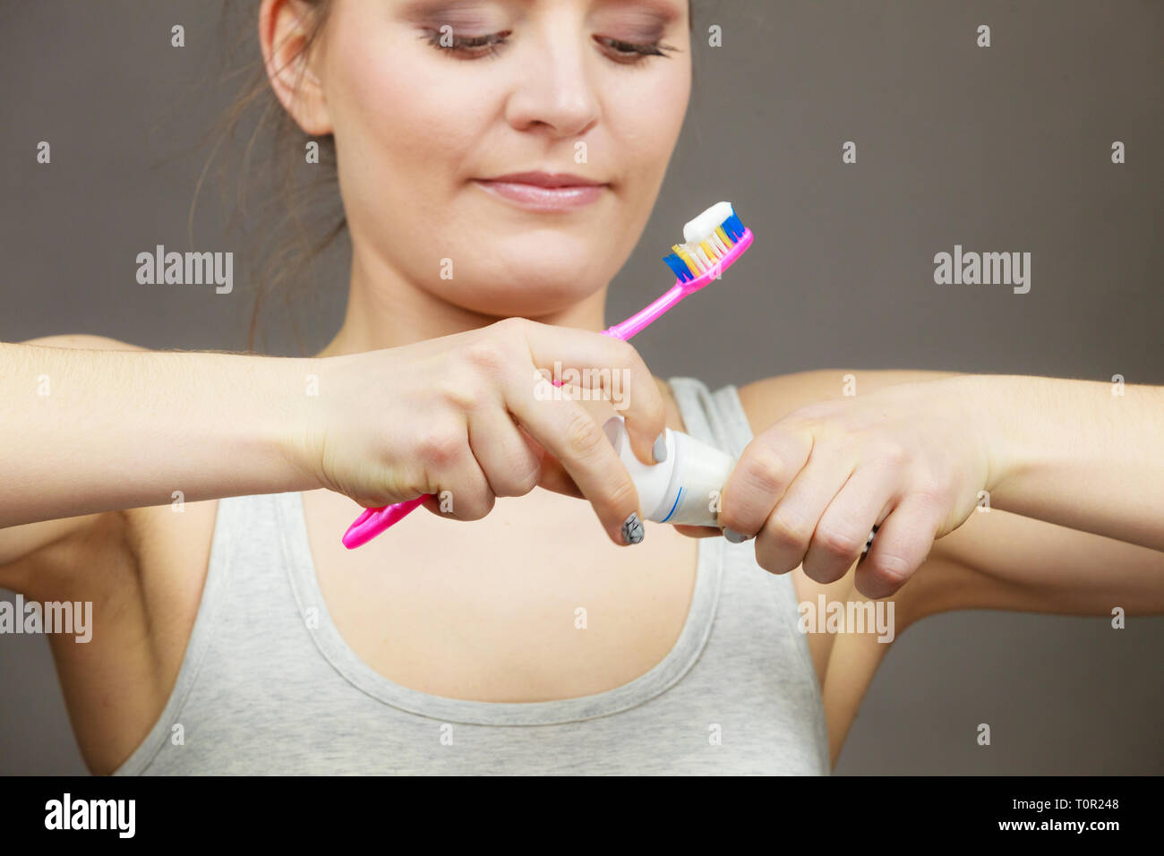Woman holding toothbrush and placing toothpaste on it. Dental health ...