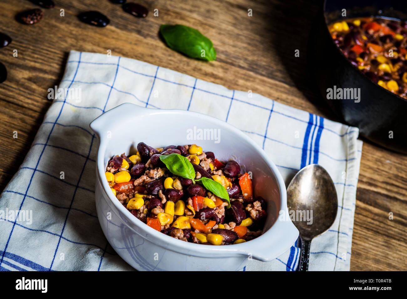 Chili or chilli corn carne. Cooked kidney bean, minced meat, chili, corn and pepper in white bowl  on wood table Stock Photo