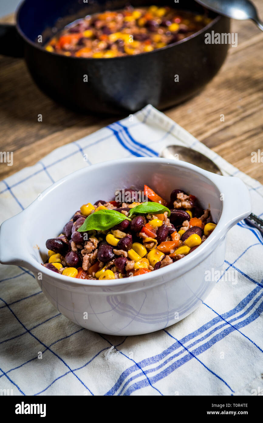 Chili or chilli corn carne. Cooked kidney bean, minced meat, chili, corn and pepper in white bowl  on wood table Stock Photo