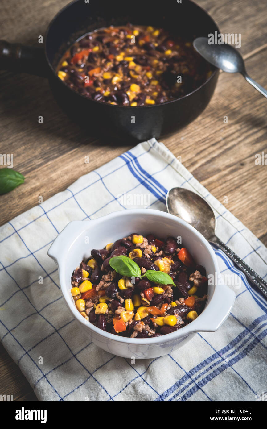 Chili or chilli corn carne. Cooked kidney bean, minced meat, chili, corn and pepper in white bowl  on wood table Stock Photo