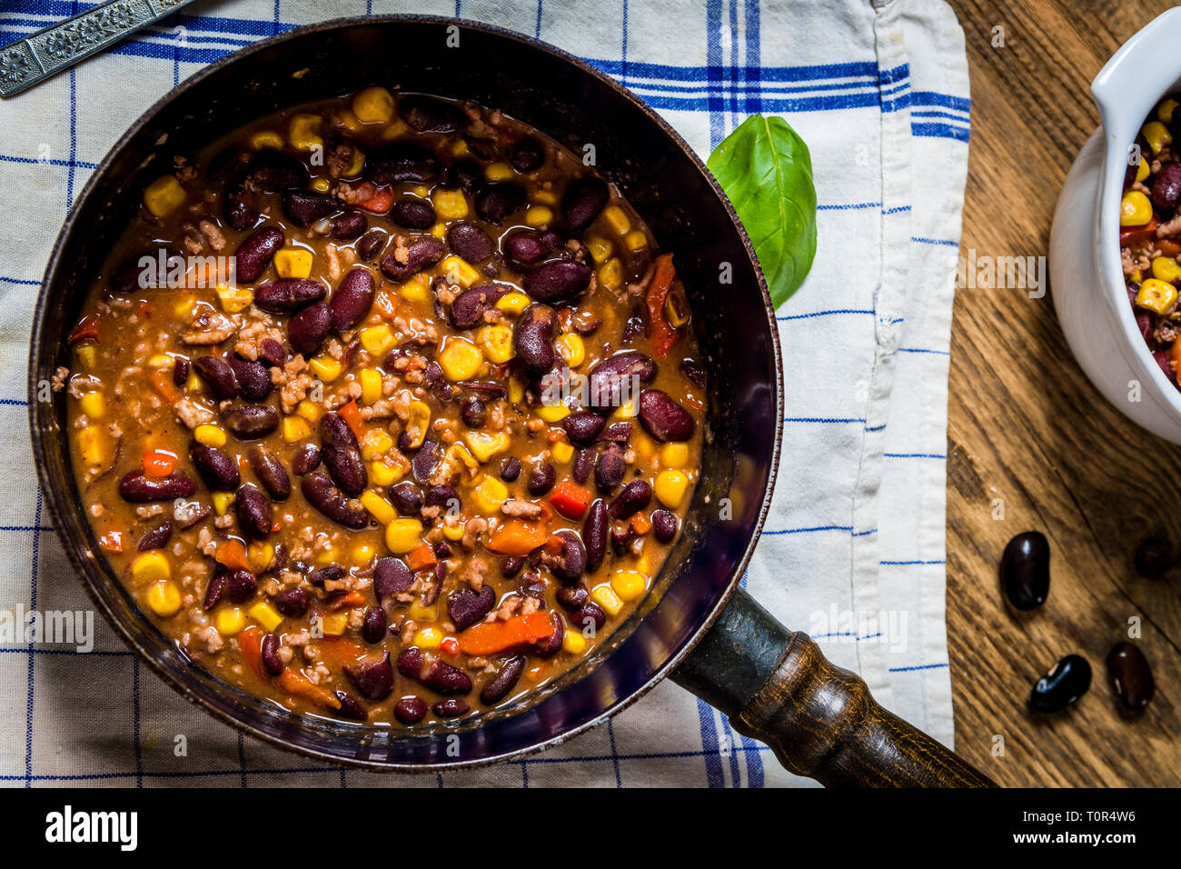Chili or chilli corn carne. Cooked kidney bean, minced meat, chili, corn and pepper in pan  on wood table top view Stock Photo