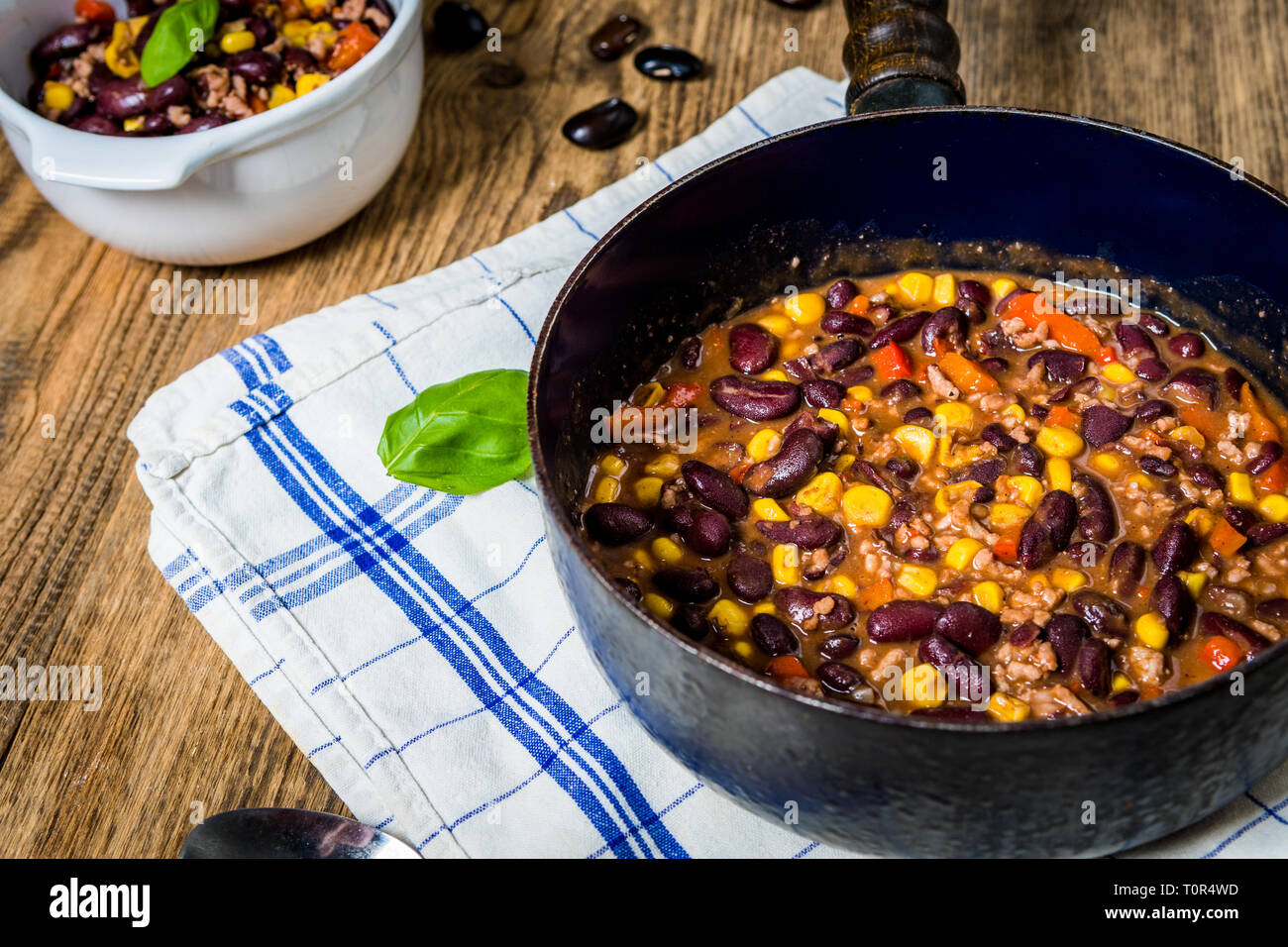 Chili or chilli corn carne. Cooked kidney bean, minced meat, chili, corn and pepper in pan  on wood table Stock Photo