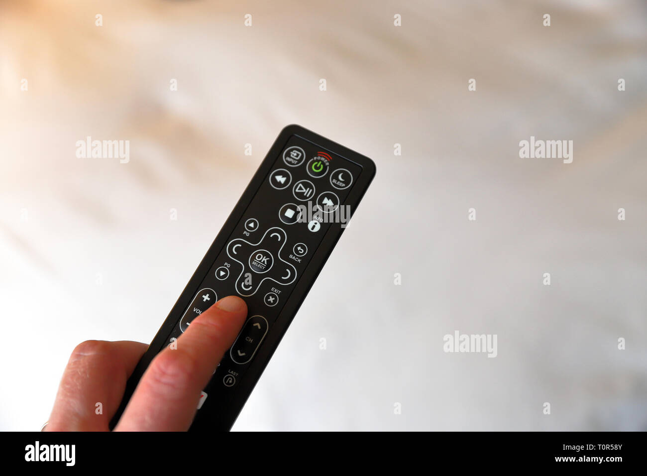 Finger pressing buttons on hotel room tv remote control, clean surface  Stock Photo - Alamy