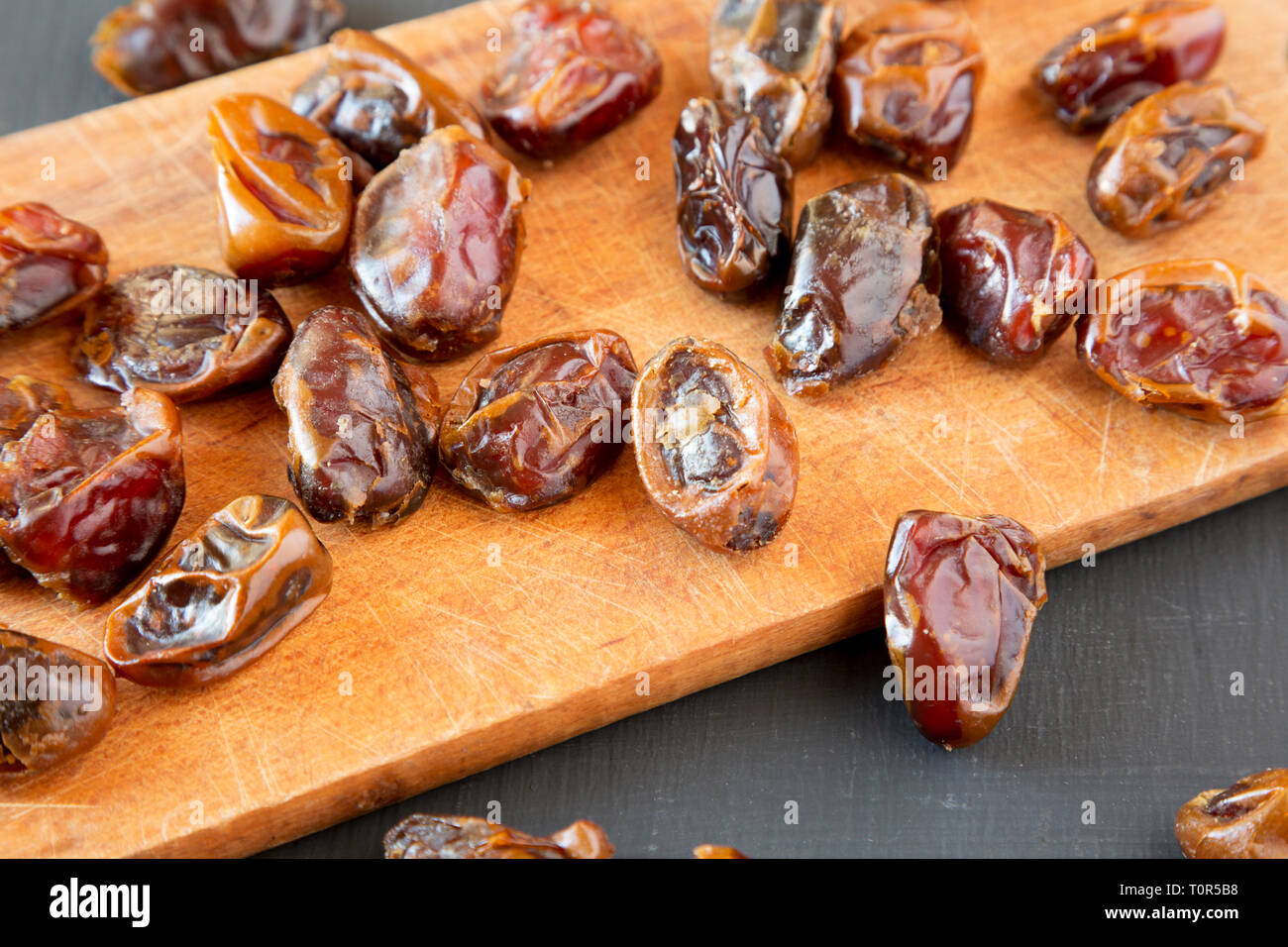 Dried dates on rustic wooden board over black surface, low angle view ...