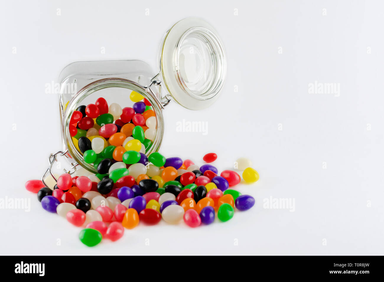 Jar of spilled jelly beans isolated on white background.  Copy space to the right. Stock Photo