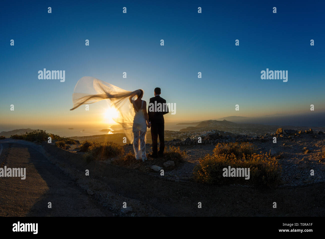 Silhouette of bride and groom on a high rock on a background of sea ...