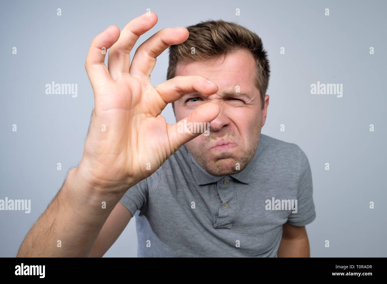 https://c8.alamy.com/comp/T0RADR/young-caucasian-man-gesturing-with-hand-showing-small-size-sign-with-fingers-T0RADR.jpg