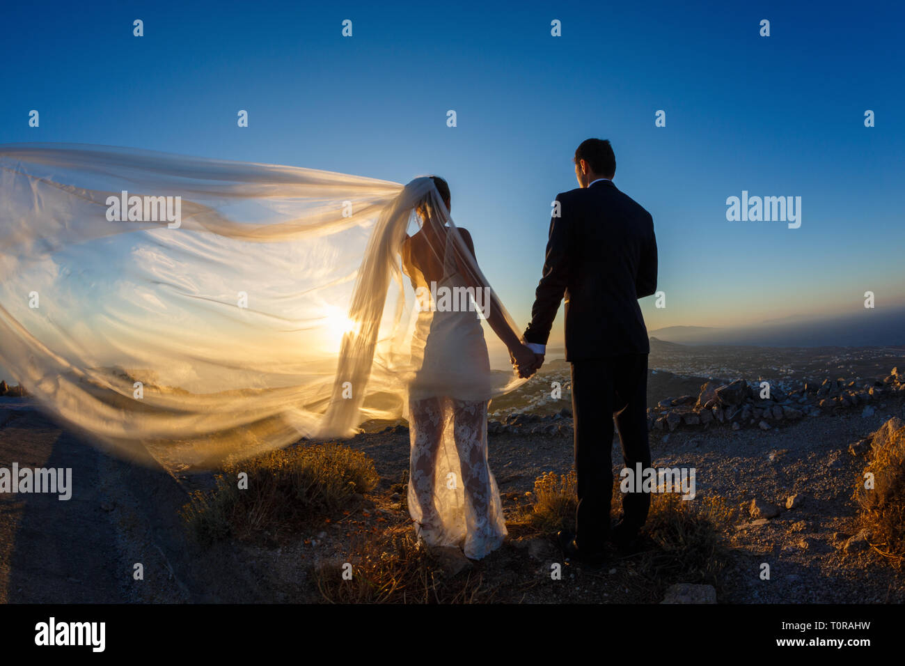 Silhouette of bride and groom on a high rock on a background of sea ...