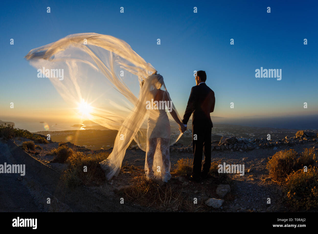 Silhouette of bride and groom on a high rock on a background of sea ...