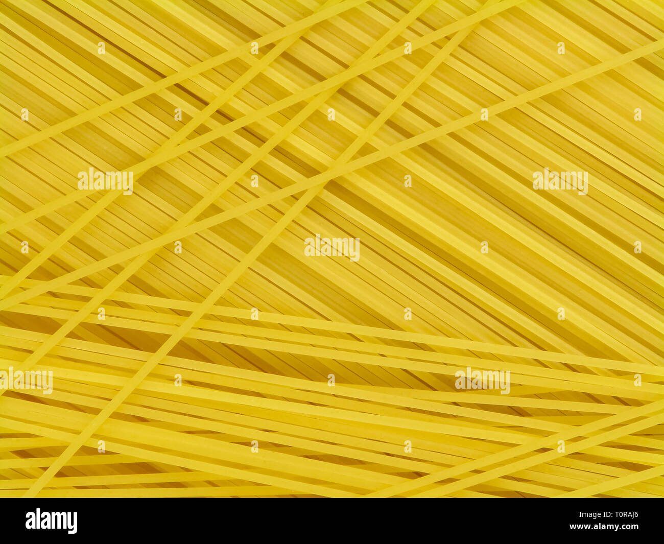 Uncooked yellow italian pasta spaghetti chaotically located top view close-up Stock Photo