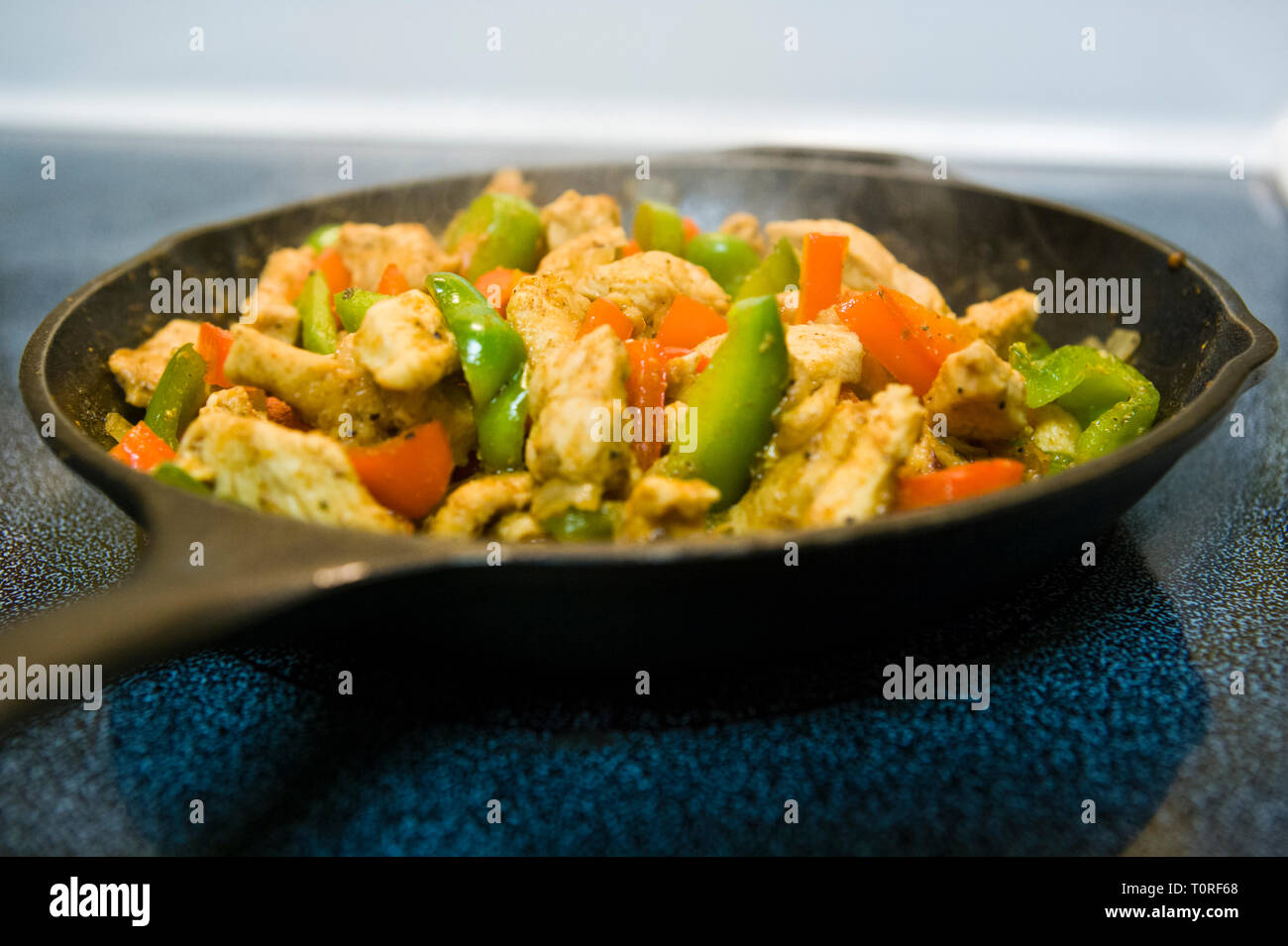 Chicken Fajitas cooking in a iron skillet on a stove top Stock Photo
