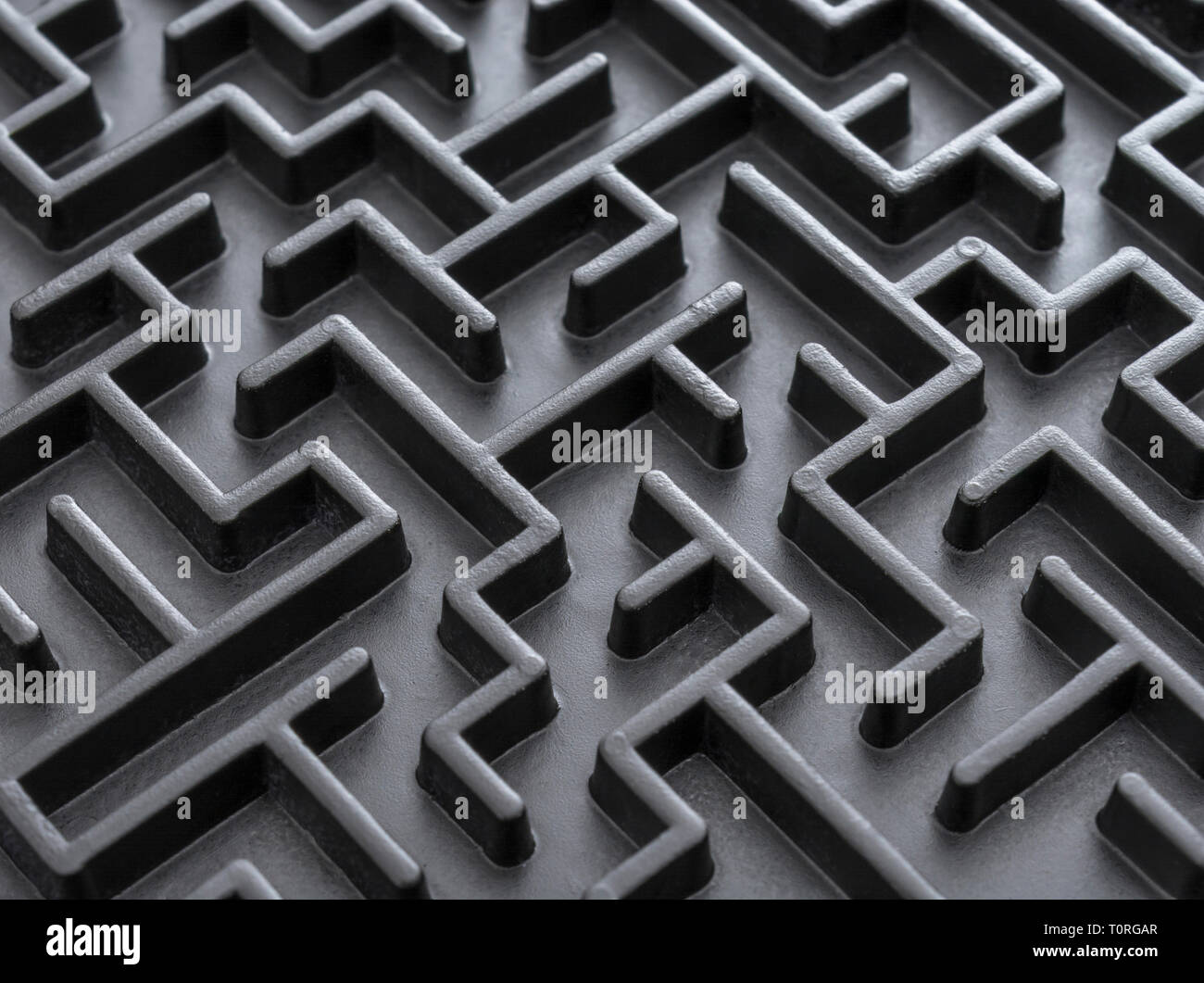 Macro shot of small toy maze painted black. For complex, getting lost, navigating, problem solving, unreachable goals, Brexit negotiations talks. Stock Photo