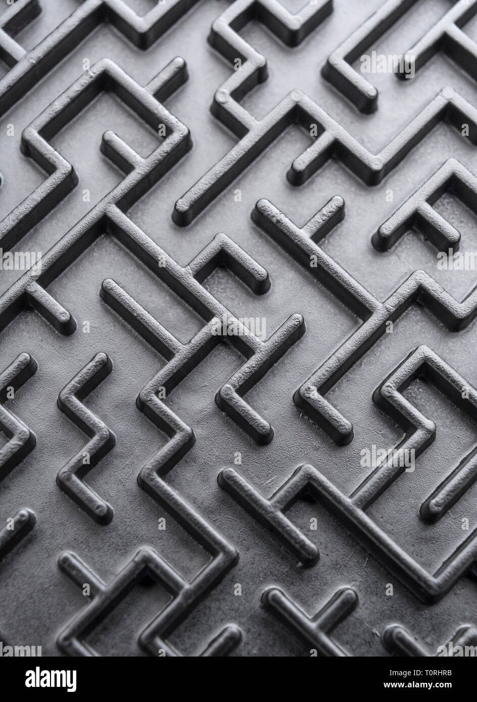Macro shot of small toy maze painted black. For complex, getting lost, navigating, problem solving, unreachable goals, Brexit negotiations talks. Stock Photo
