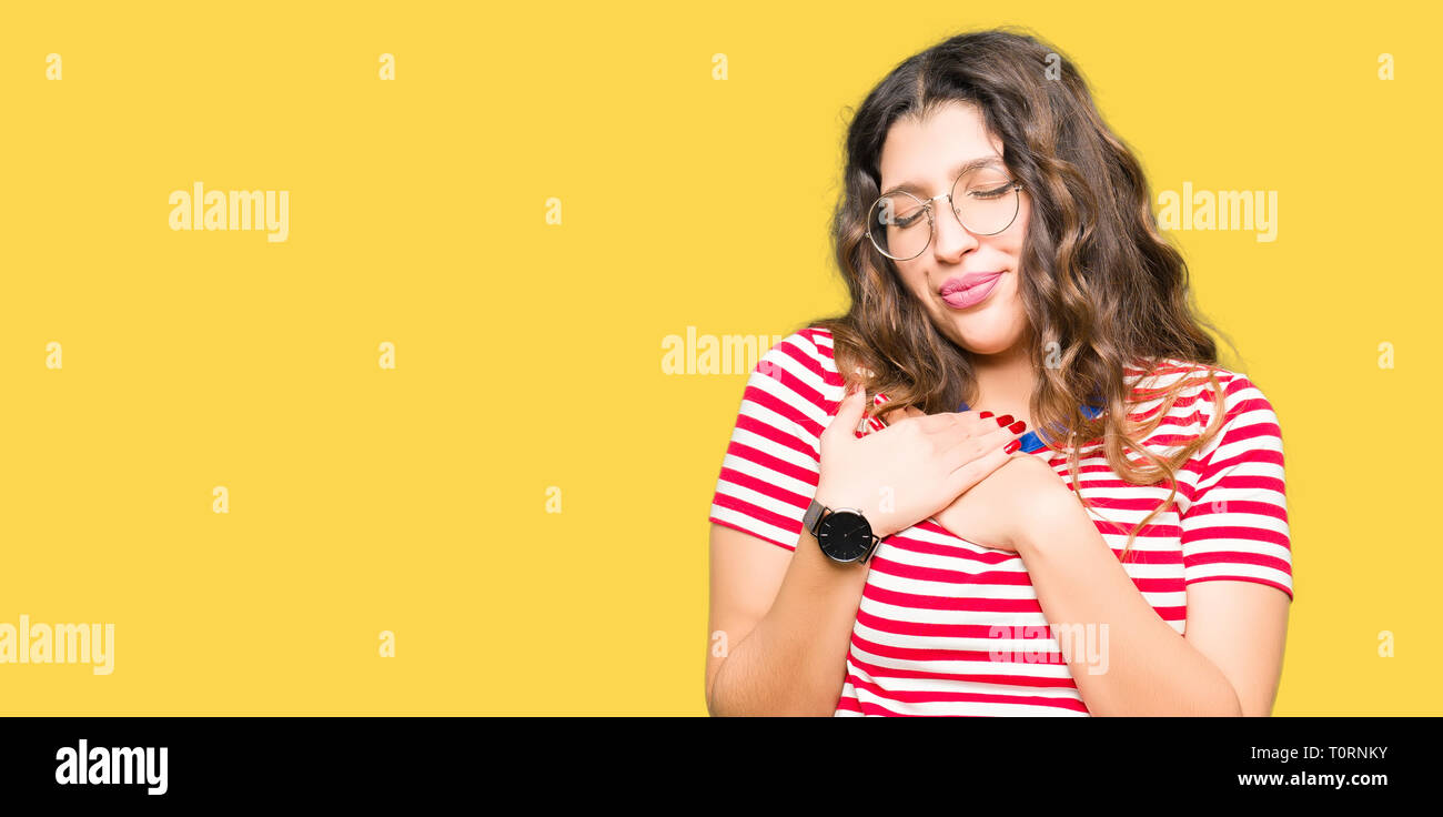 Young beautiful woman wearing glasses smiling with hands on chest with closed eyes and grateful gesture on face. Health concept. Stock Photo