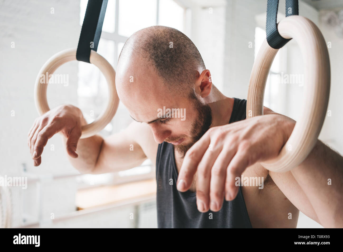 Tired Handsome Strong Man Holding On To Gymnastic Rings At