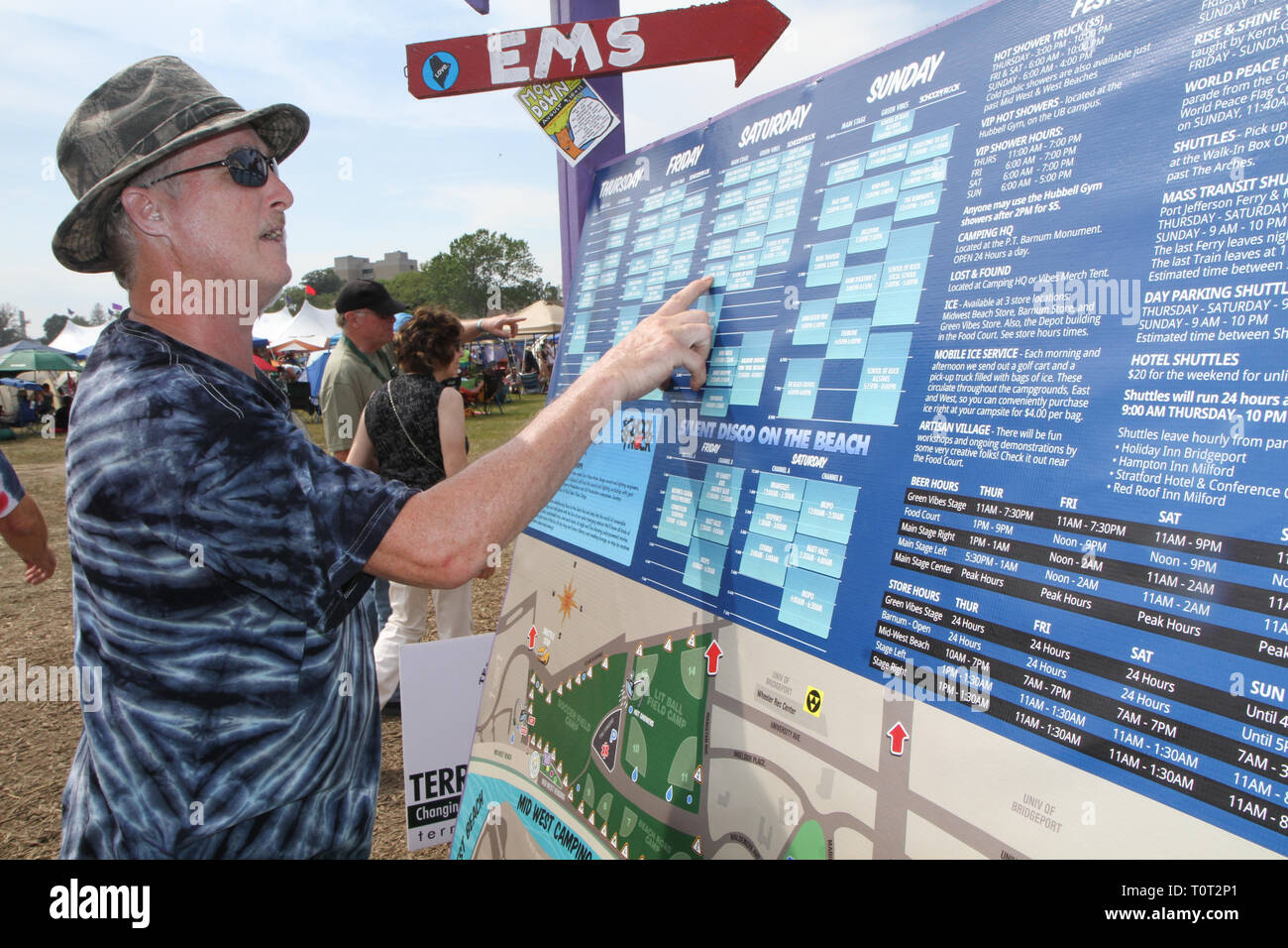 A concert goer is shown checking the Band Schedule Board at an outdoor summer music festival. Stock Photo