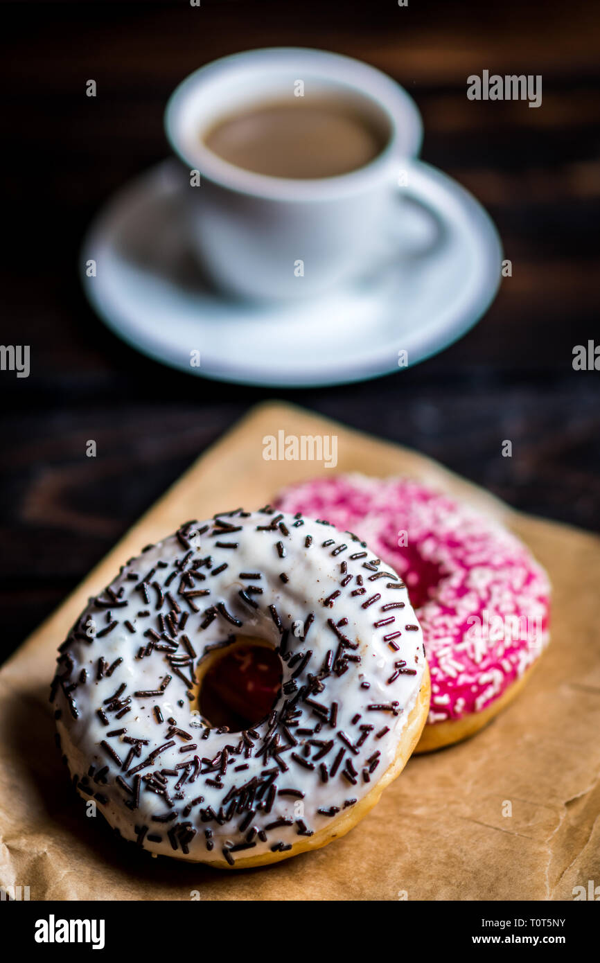 Pink and white donuts with sprinkle and cup of coffee on wood table Stock Photo
