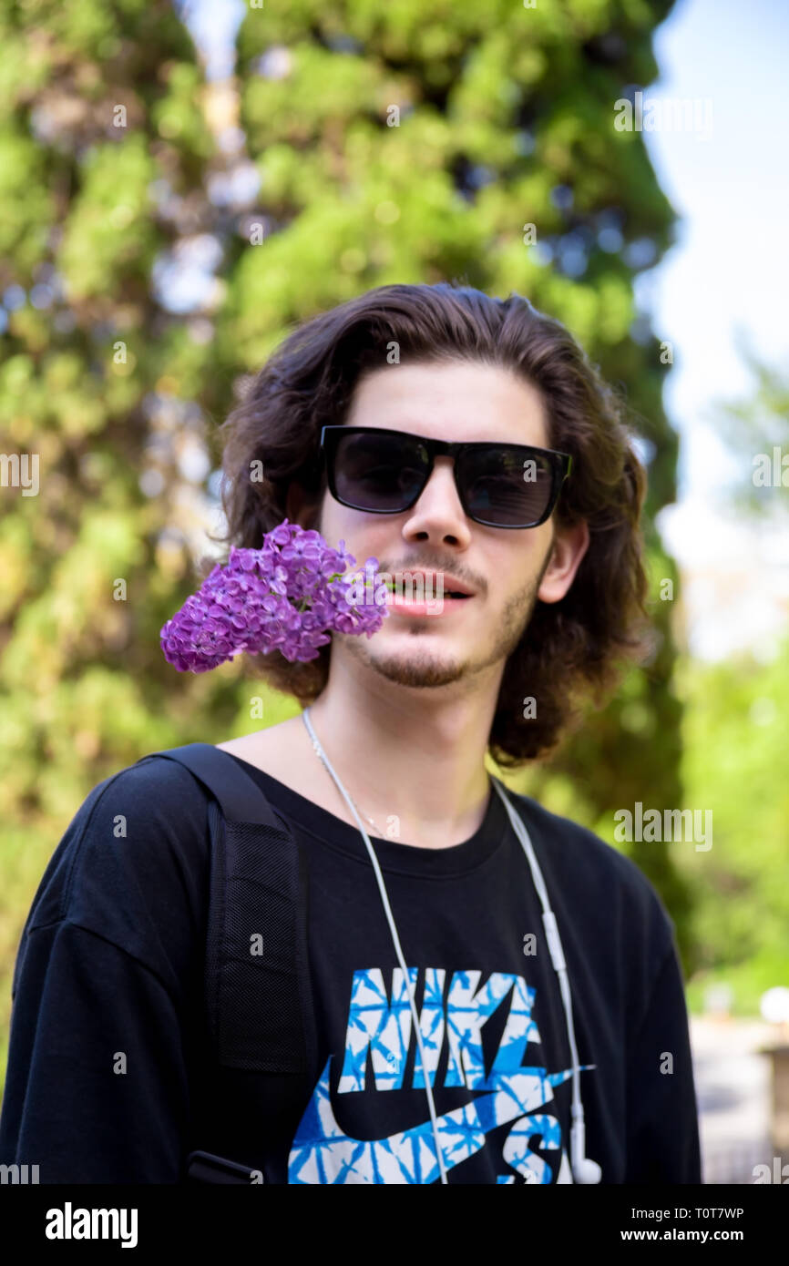 Young Brunette Man With Long Curly Hair And Sunglasses Holds Fresh