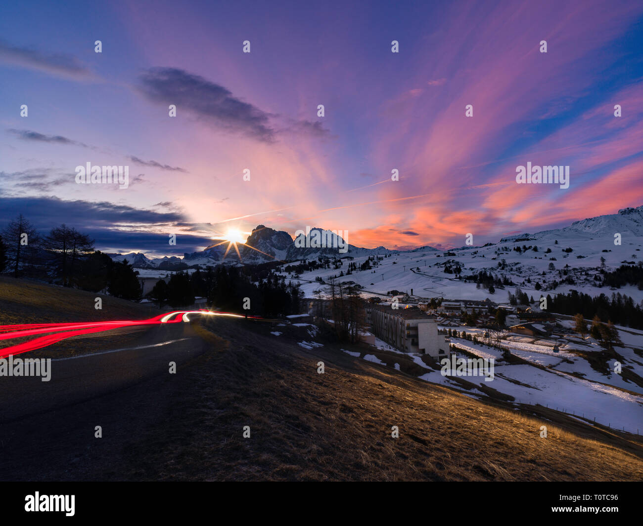 Beautiful sunrise in Dolomites, car light trails heading into mountains Stock Photo