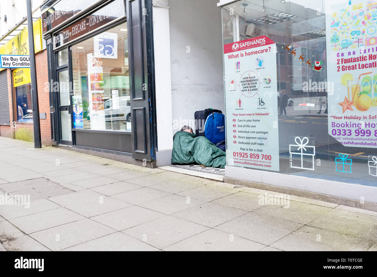 Homeless man sleeps rough in a shop doorway in Warrington Town Centre, Cheshire, UK Stock Photo