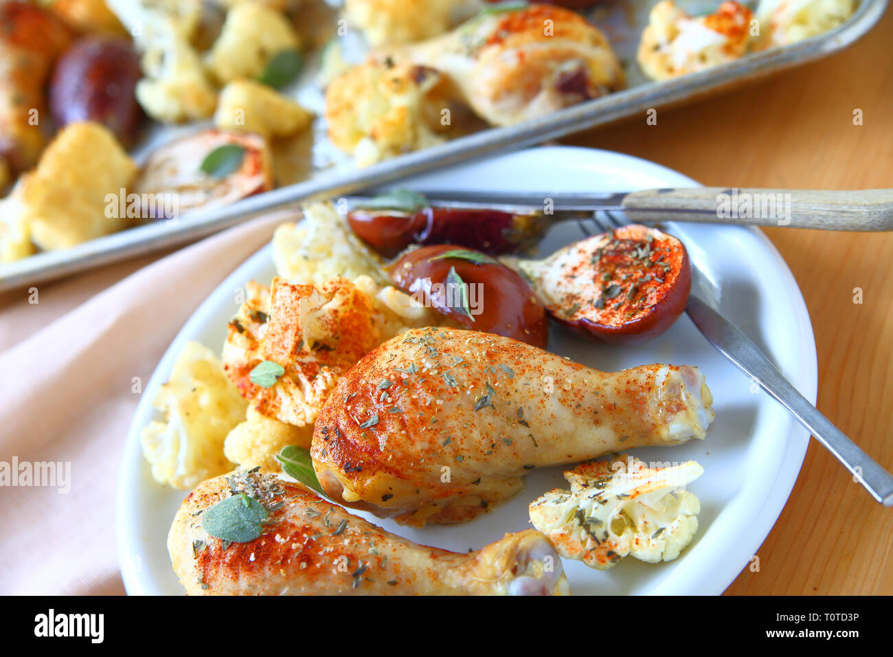 Plate of roasted chicken legs, mini eggplants and cauliflower seasoned
