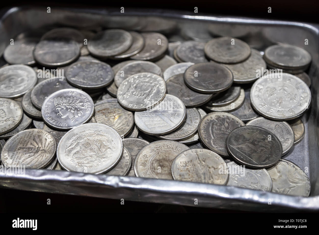 Pile of metal coins of different denominations and different countries in metal box Stock Photo