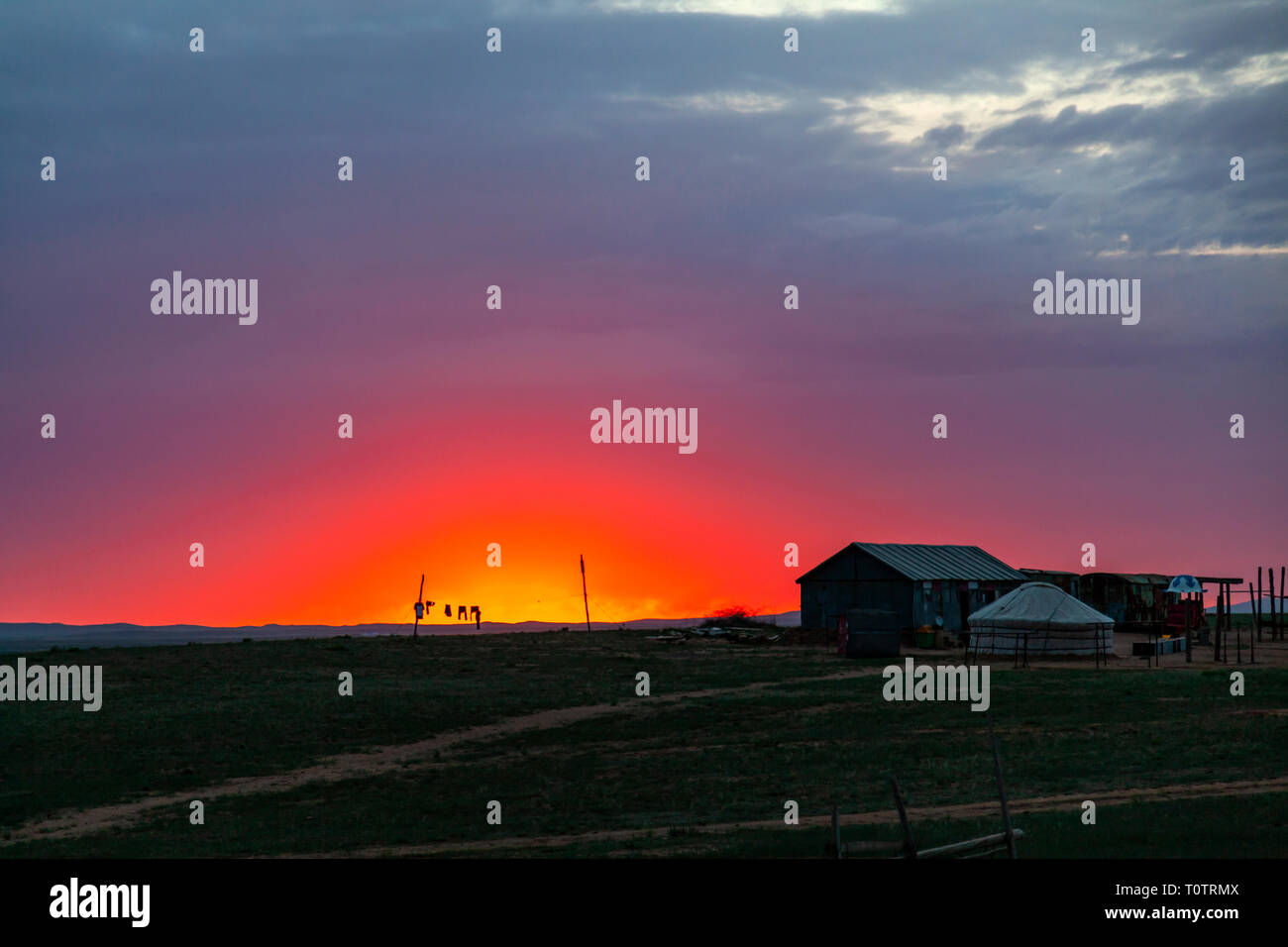Sunrise over the Gegentala grasslands north of Hohhot, Inner Mongolia, China. Some clothes hanging to dry outside a house and a ger (yurt). Stock Photo