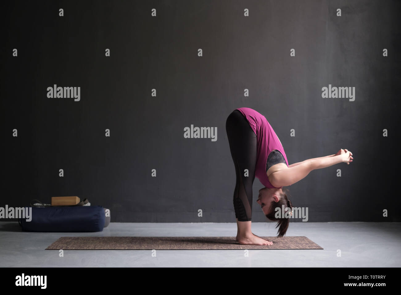 Sporty woman practicing yoga, standing forward bend exercise, uttanasana pose. Stock Photo