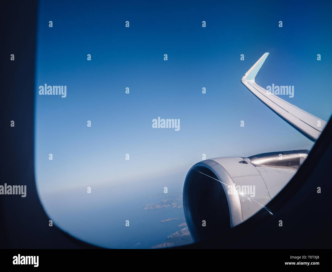 View from window of plane turbine in flight high above clouds in sunlight security transportation business class Stock Photo