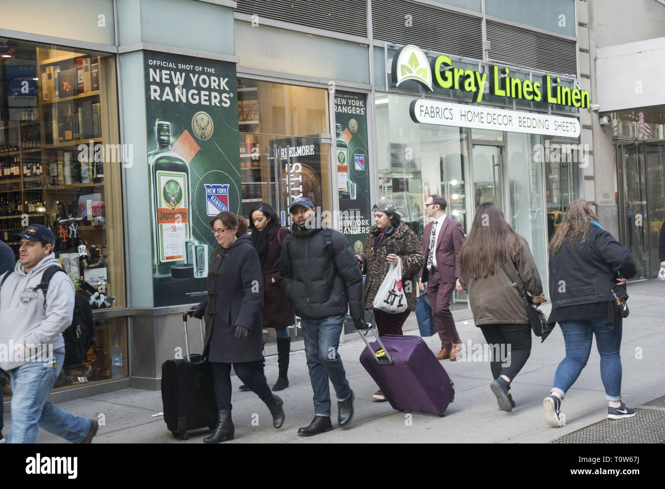 7th Avenue near Penn Station is always crowded with New Yorkers and visitors dragging luggage with them. Stock Photo