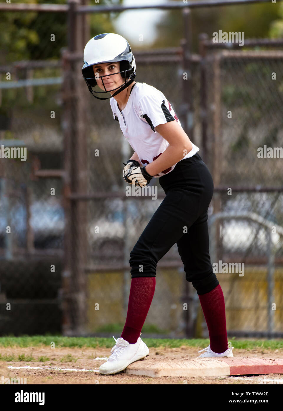 Female teen softball player in black and white uniform showing wide