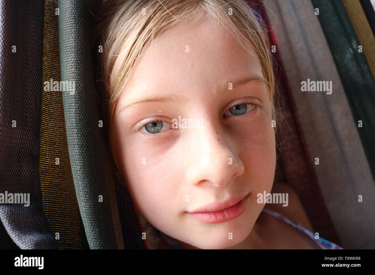 Portrait of a young wet blond girl with blue eyes contently resting in a hammock Stock Photo
