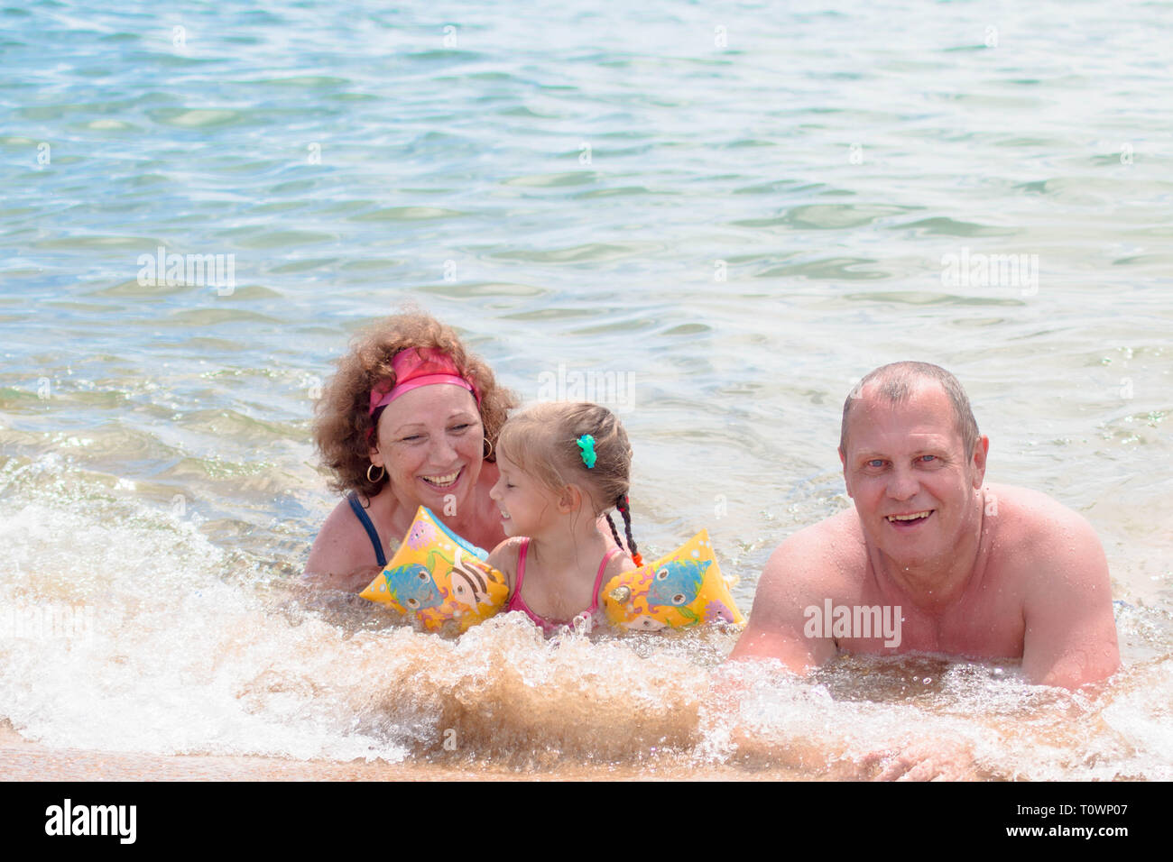 Grandparents And Granddaughter swimming in the sea, they smile and happyness. Stock Photo
