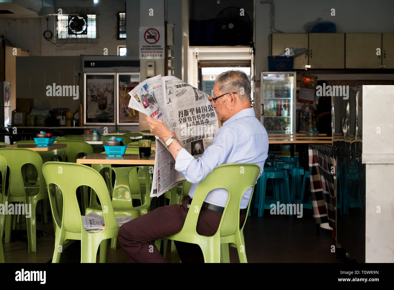 A gentleman reads a Chinese language newspaper in Kota Kinabalu, Sabah, Borneo, Malaysia. Stock Photo
