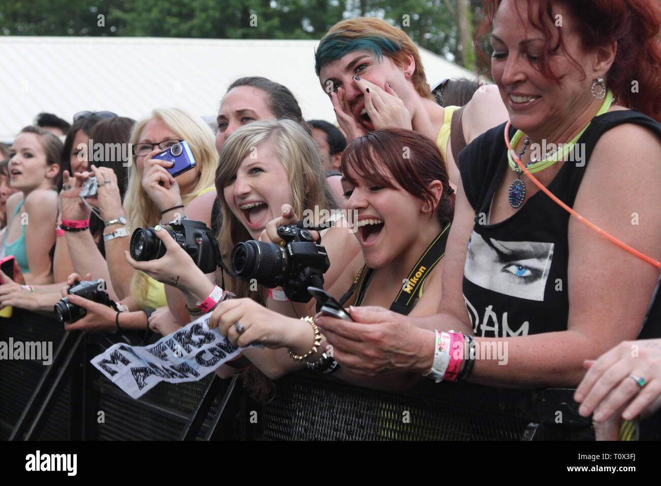 Happy front row fans are shown before the start of an outdoor concert performance. Stock Photo